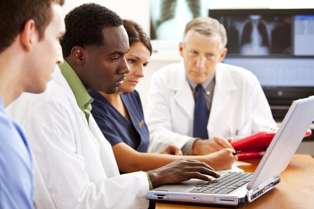 Doctors collaborating on patient information at a computer.