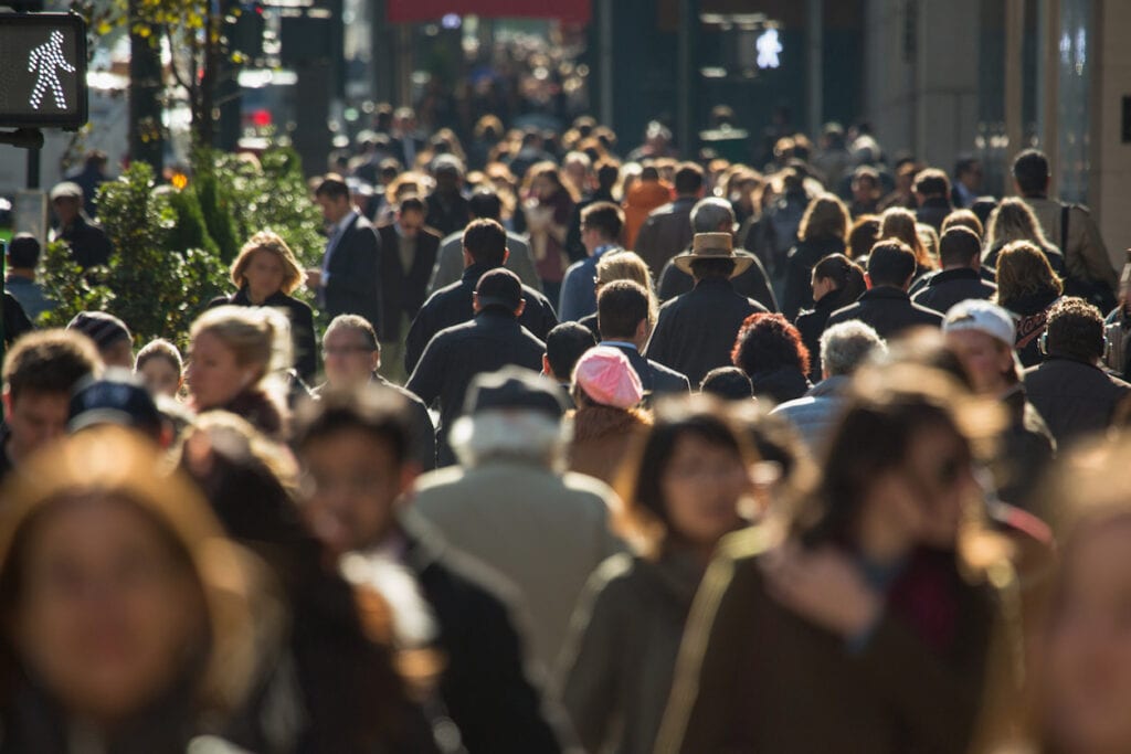 Crowded city street filled with people walking in various directions.