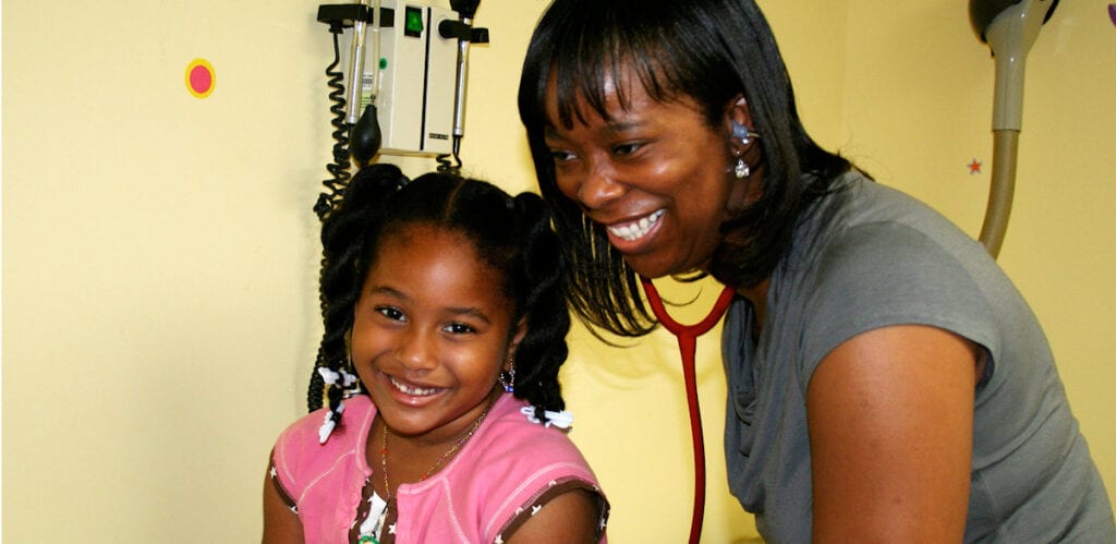 A smiling child and woman share a joyful moment.