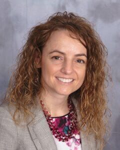 Professional woman with curly hair smiling in a headshot.