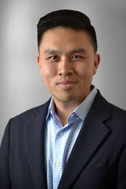 Portrait of a man in a suit smiling gently.