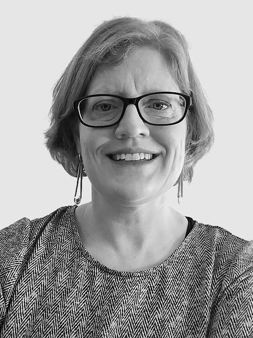 Smiling middle-aged woman wearing glasses and a patterned top.