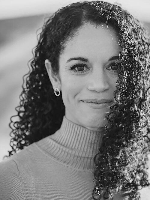 Black and white portrait of a woman with curly hair smiling gently.