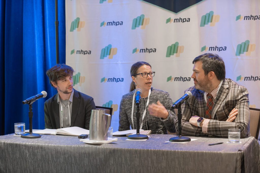 Three professionals engaged in a discussion at a conference panel.